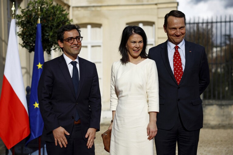 French Foreign and European Affairs Minister Stephane Séjourn, left, German Foreign Minister Annalena Baerbock, center, and Polish Foreign Minister Radoslaw Sikorski attend Weimar Triangle talks at the Château de la Salle Saint-Cloud near Paris on Monday, Feb. Posing while reaching for.  12, 2024. The foreign ministers of France, Germany and Poland are to meet as they seek to revive the so-called Weimar Triangle, a political format that has been dormant for years.  The Weimar Triangle was created in 1991 when Poland was emerging from decades of communism as a platform for political cooperation between the three countries.  (Sarah Messonnier, Pool via AP)