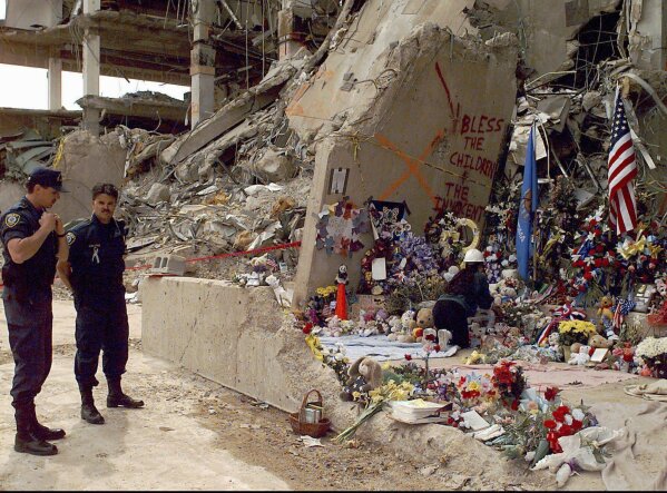 Officials stand near the Alfred P. Murrah Federal Building as workers place flowers and memorial items at the scene of the explosion in Oklahoma City on May 5, 1995. (AP Photo/J. Pat Carter, File)