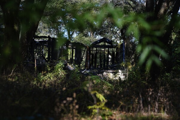 Excessive overgrowth fills a yard Wednesday, Dec. 6, 2023, in Prichard, Ala., around the remains of a home that burned. Prichard loses up to 60% of its treated water through leaks, sometimes making it difficult to fight fires. (AP Photo/Brynn Anderson)