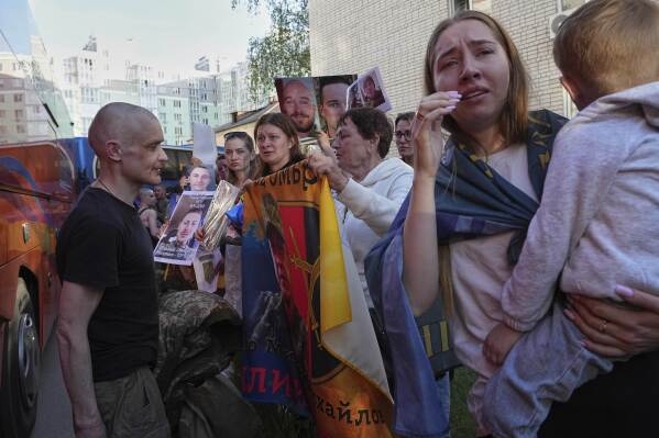 Family members of Ukrainian prisoners hold photos of servicemen in captivity during a POWs exchange between Russia and Ukraine, in Chernyhiv region, Ukraine, Friday, May 23, 2025. (AP Photo/Efrem Lukatsky)