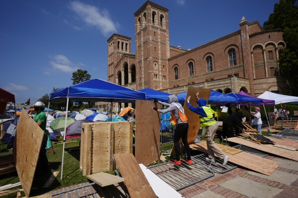 Manifestantes restauram uma barreira de segurança em um acampamento no campus da UCLA após confrontos entre grupos pró-Israel e pró-Palestina, quarta-feira, 1º de maio de 2024, em Los Angeles.  (Foto AP/Jay C. Hong)