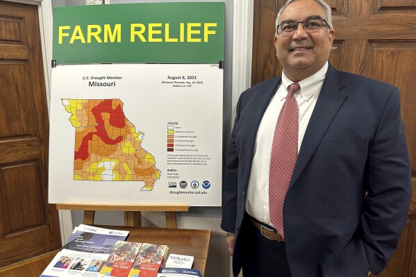 FILE - Missouri Treasurer Vivek Malek stands near a poster promoting drought conditions and state aid programs, Jan. 4, 2024, at his Capitol office in Jefferson City, Mo. Agricultural entities are among several categories of businesses that can receive low-interest loans backed by deposits of state funds made by the treasurer's office. Missouri lawmakers gave final approval Thursday, April 18, to significantly expand a low-interest loan program for farmers and small businesses. (AP Photo/David A. Lieb, File)