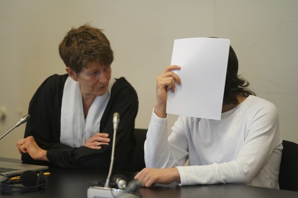 The defendant, right, a suspected IS returnee, sits next to his lawyer Gabriele Heinecke at the beginning of the trial day in the courtroom in the Criminal Justice Building in Hamburg, Germany, Wednesday, July 19, 2023. A German woman convicted on charges that she and her husband allowed the death by thirst of a 5-year-old Yazidi girl she and her husband kept as a slave when they were members of the Islamic State group in Iraq has expressed remorse at the start of a new sentencing hearing. (Marcus Brandt/dpa via AP)