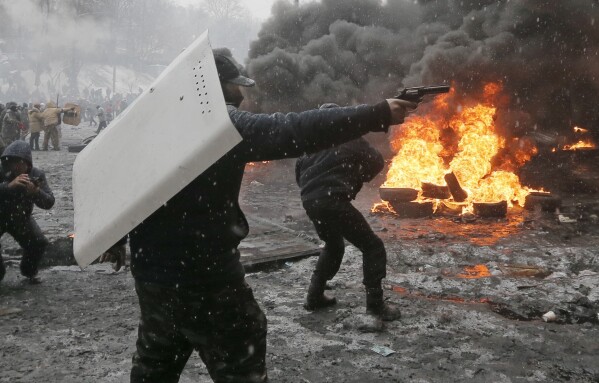 FILE - In this file photo taken on Jan. 22, 2014, a protester points a handgun during a clash with police in central Kyiv, Ukraine. On Nov. 21, 2023, Ukraine marks the 10th anniversary of the uprising in Ukraine that eventually led to the ouster of the country’s Moscow-friendly president. (AP Photo/Efrem Lukatsky, file)