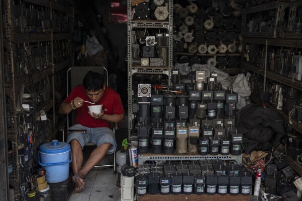 Bao Loc eats his lunch in his shop packed with refurbished gear motors in Nhat Tao market, the largest informal recycling market in Ho Chi Minh City, Vietnam, Monday, Jan. 29, 2024. (AP Photo/Jae C. Hong)
