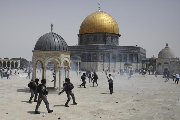 FILE - Palestinians run from sound grenades thrown by Israeli police in front of the Dome of the Rock in the Al-Aqsa Mosque complex in Jerusalem, Friday, May 21, 2021, as a cease-fire took effect between Hamas and Israel after an 11-day war. (AP Photo/Mahmoud Illean, File)