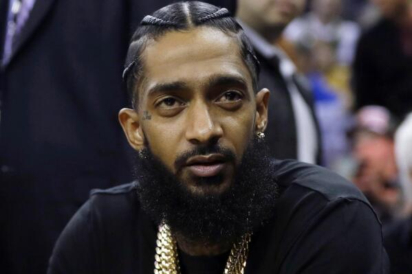 FILE - Rapper Nipsey Hussle attends an NBA basketball game between the Golden State Warriors and the Milwaukee Bucks in Oakland, Calif., March 29, 2018. Eric R. Holder Jr., who was convicted last year of fatally shooting Hussle in 2019, is scheduled to be sentenced Wednesday, Feb. 22, 2023, in a Los Angeles courtroom. (AP Photo/Marcio Jose Sanchez, File)