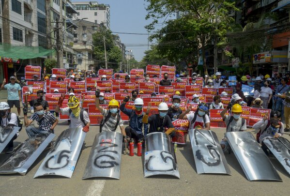 Anti-coup protesters display placards as they gather in Yangon, Myanmar Tuesday, March 16, 2021. A grassroots movement has sprung up across the country to challenge the military's seizure of power with almost daily protests that the army has tried to crush with increasingly deadly violence. (AP Photo)