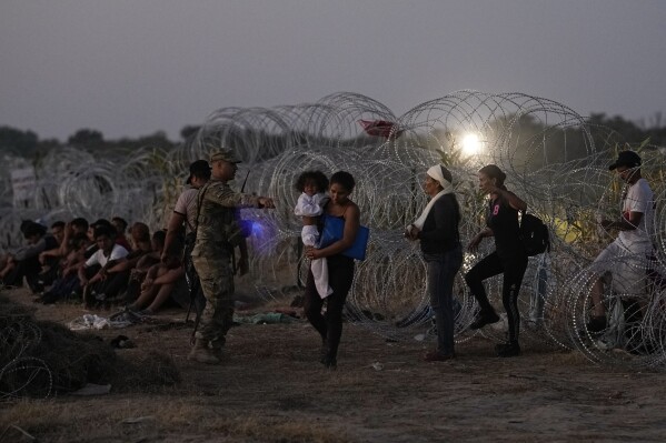 FILE - Migrants who crossed the Rio Grande and entered the U.S. from Mexico are lined up for processing by U.S. Customs and Border Protection, Saturday, Sept. 23, 2023, in Eagle Pass, Texas. Congress is discussing changes to the immigration system in exchange for providing money to Ukraine in its fight against Russia and Israel for the war with Hamas. (AP Photo/Eric Gay, File)