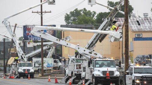 Line workers in boom trucks and on the street work to replace broken utility poles and lines as rain moves in on Peoria Avenue over the Broken Arrow Expressway, Wednesday, June 21, 2023, in Tulsa, Okla. (Daniel Shular/Tulsa World via AP)