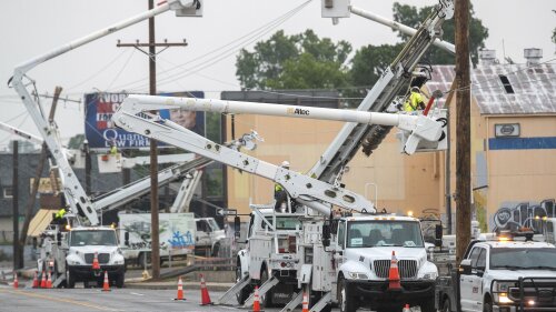 Les travailleurs de la ligne dans des camions à flèche et dans la rue travaillent pour remplacer les poteaux et les lignes électriques cassés alors que la pluie s'abat sur l'avenue Peoria au-dessus de l'autoroute Broken Arrow, le mercredi 21 juin 2023, à Tulsa, Okla. (Daniel Shular/Tulsa World via AP )