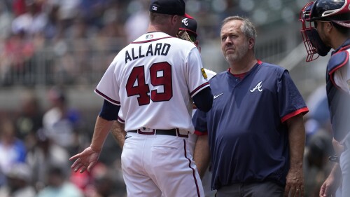 A member of Atlanta Braves training staff checks on pitcher Kolby Allard (49) in the second inning of a baseball game against the Chicago White Sox Sunday, July 16, 2023, in Atlanta. Allard left the game. (AP Photo/John Bazemore)