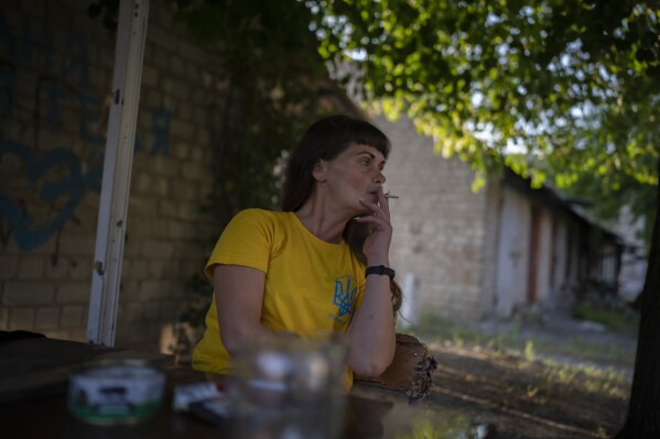 Olena Kanivets smokes a cigarette outside her home in Kupiansk-Vuzlovyi, Ukraine, Wednesday, Aug. 23, 2023. (AP Photo/Bram Janssen)