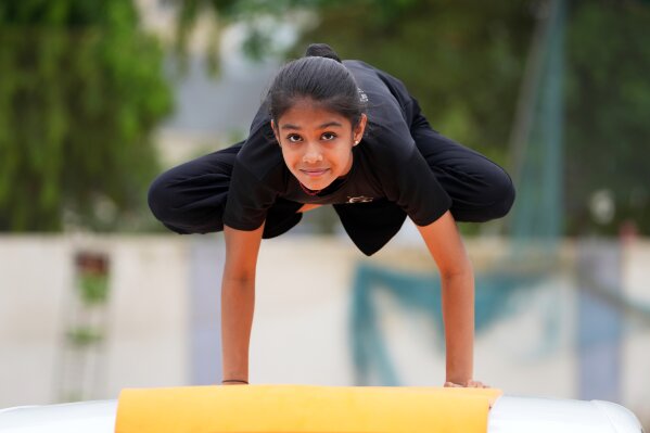 A girl performs yoga on top of a parked car as members of a yoga institute celebrate International Day of Yoga in Ahmedabad, India, Saturday, June 21, 2025. (AP Photo/Ajit Solanki)