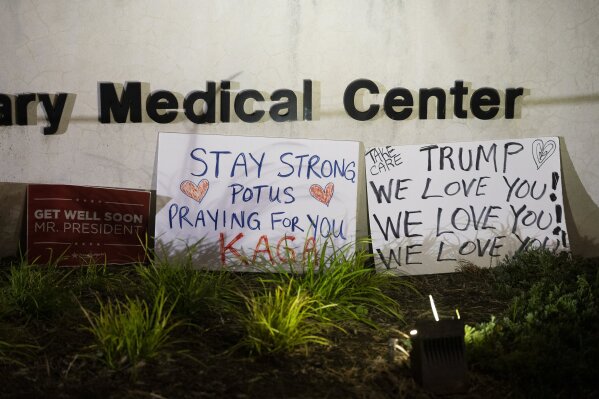 Signs left by supporters of President Donald Trump at the entrance to Walter Reed National Military Medical Center in Bethesda, Md., Sunday, Oct. 4, 2020. Trump was admitted to the hospital after contracting the coronavirus. (AP Photo/Cliff Owen)