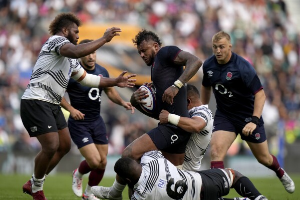 England's captain Courtney Lawes, centre, is tackled by Fiji's Sam Matavesi, right, and teammate Albert Tuisue, bottom, during the rugby union international match between England and Fiji at Twickenham stadium in London, Saturday, Aug. 26, 2023. (AP Photo/Alastair Grant)