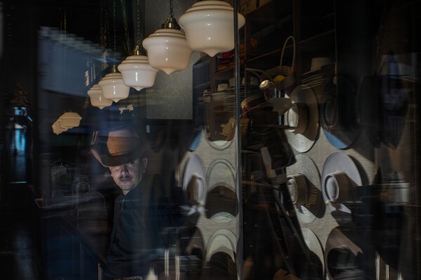 An employee waits for customers at the “Donde Golpea el Monito” hat shop and museum that preserves a hat-making tradition dating back to 1915, in Santiago, Chile, Thursday, April 3, 2025. (AP Photo/Esteban Felix)