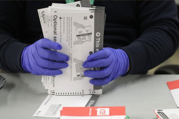 A worker wears gloves while handling ballots from the Washington state primary election, Tuesday, March 10, 2020, at the King County Elections headquarters in Renton, Wash. Protective gloves are mandatory this election for ballot processing workers in light of the outbreak of the novel coronavirus in Washington state. (AP Photo/Ted S. Warren)