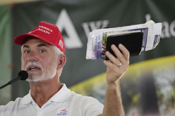 Candidate for the Republican nomination for Governor, Dr. John Witcher holds out his Bible as he addresses the crowd at the Neshoba County Fair in Philadelphia, Miss., Thursday, July 27, 2023. Witcher faces David Hardigree and incumbent Mississippi Gov. Tate Reeves for the party's nomination on Aug. 8. (AP Photo/Rogelio V. Solis)