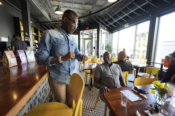 Hamissi Mamba talks to customers at his restaurant, Baobab Fare, Friday, May 24, 2024, in Detroit. For Hamissi Mamba and Nadia Nijimbere _ who own Baobab Fare in Detroit _ a win among the five finalists in the James Beard's "Outstanding Restaurateur" category would be personal. The couple, who fled Burundi about a decade ago, faced a difficult road as refugees opening a business in America. (AP Photo/Carlos Osorio)