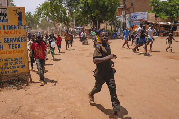Children run in the streets of Niamey, Niger, Sunday, Aug. 13, 2023. People marched, biked and drove through downtown Niamey, chanting 