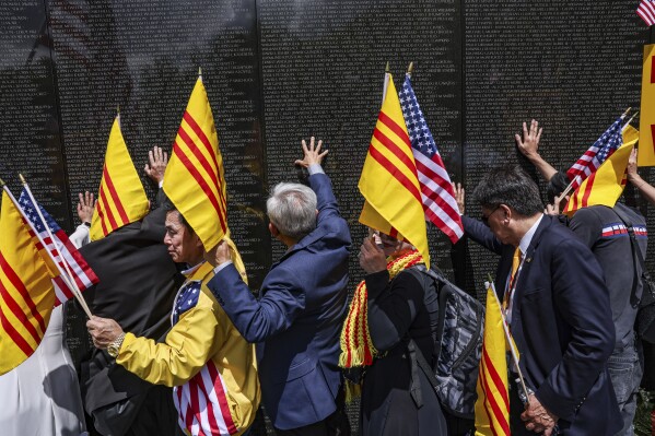 Vietnamese-Americans place their hands on the Vietnam Veterans Memorial to honor American soldiers who died in the Vietnam War, as they gather together in commemoration of the 50th Anniversary of the fall of Saigon, Wednesday, April 30, 2025, in Washington. (AP Photo/Valerie Plesch)