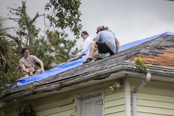 Residents repair their roof as high winds from an outer band from Tropical Storm Debby passed over the Isle of Palms, S.C., Tuesday, Aug. 6, 2024. (AP Photo/Mic Smith)