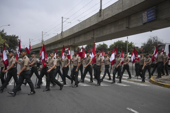 Police officers with national flags make their way to the Ministry of Culture, the venue for the Asia-Pacific Economic Cooperation (APEC) summit, in Lima, Peru, Friday, Nov. 15, 2024. (AP Photo/Guadalupe Pardo)