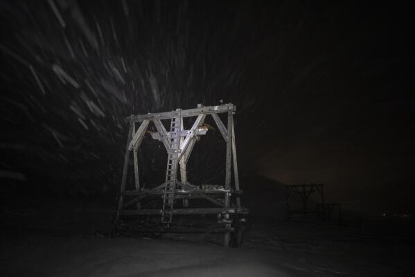 Snow falls on a disused wire rope tramway in Adventdalen, Norway, Monday, Jan. 9, 2023. For more than 100 years, people came to the remote Arctic archipelago of Svalbard to work in coal mines. (AP Photo/Daniel Cole)