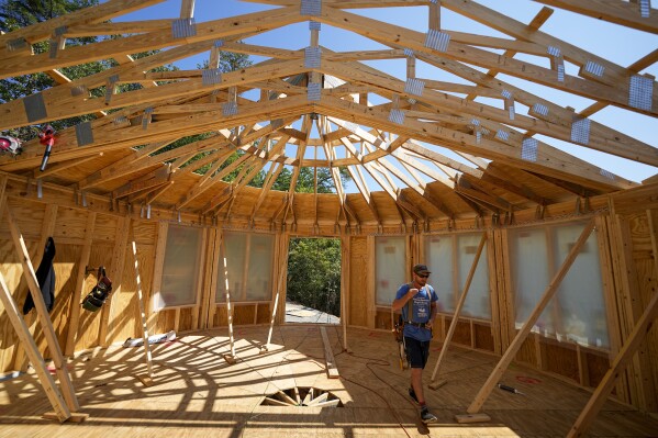 Workers build a home Tuesday, Sept. 19, 2023, in Marshall, N.C. Climate change is increasing billion-dollar disasters, many of them from intensifying hurricanes. Housing developers are now building homes, some of them round, that can resist hurricane-force winds and at the same time generate much less of the emissions that contribute to climate change. (AP Photo/Chris Carlson)