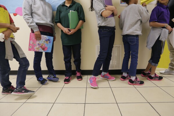 FILE - Migrant teens line up for a class at a "tender-age" facility for babies, children and teens, in Texas' Rio Grande Valley, in San Benito, Texas, Aug. 29, 2019. The Biden administration struggled to properly vet and monitor the homes where they placed a surge of migrant children who arrived at the U.S.-Mexico border in 2021. That's according to a federal watchdog report released Thursday. (AP Photo/Eric Gay File)