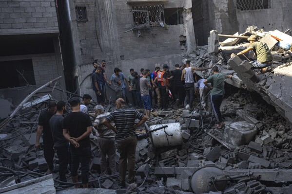 Palestinians search for bodies and survivors in the rubble of a residential building leveled in an Israeli airstrike, Al Shati Refugee Camp Thursday, Oct. 12, 2023. Israel's retaliation has escalated after Gaza's militant Hamas rulers launched an unprecedented attack on Israel Saturday, killing over 1,200 Israelis and taking captive dozens. Heavy Israeli airstrikes on the enclave has killed over 1,200 Palestinians. (AP Photo/Fatima Shbair)