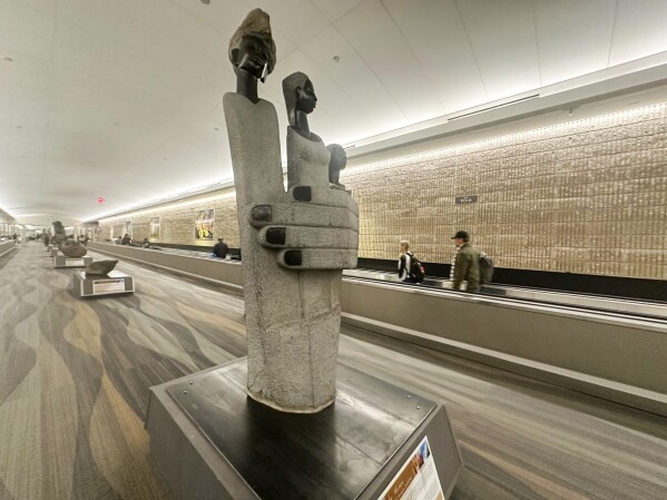 People walk by a Zimbabwean sculpture piece at Hartsfield-Jackson Atlanta International Airport, Friday, Feb. 28, 2025, in Atlanta. (AP Photo/Ravi Nessman)
