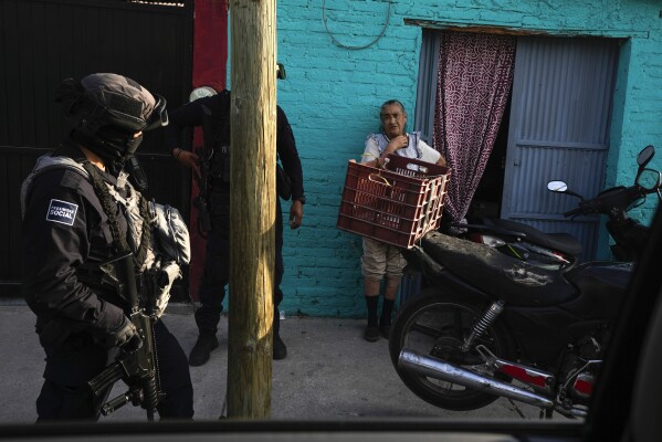 Municipal police chat with a resident while patrolling her neighborhood in Celaya, Mexico, Wednesday, Feb. 28, 2024. Celaya, a farming and industrial hub northwest of Mexico City, has refused to eliminate its local police force, like some cities that instead rely almost completely on soldiers and the National Guard for policing. (AP Photo/Fernando Llano)