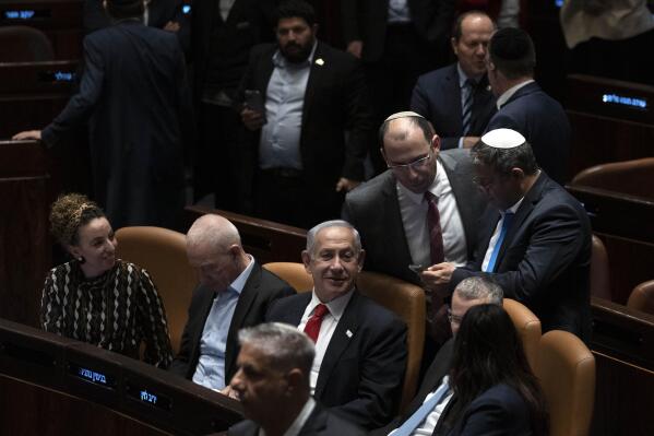 Israel's Prime Minister Benjamin Netanyahu, center, and lawmakers congratulate Justice Minister Yariv Levin, in blue tie at right foreground, after his speech in Israel's parliament, the Knesset, just before a vote on a contentious plan to overhaul the country's legal system, in Jerusalem, early Tuesday, Feb. 21, 2023. (AP Photo/Maya Alleruzzo, Pool)