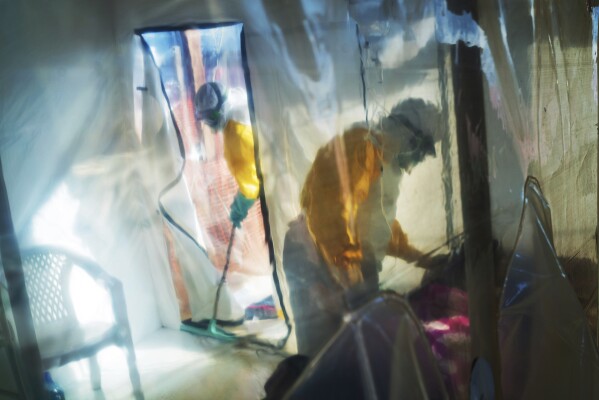 FILE - Health workers wearing protective suits tend to to an Ebola victim kept in an isolation tent in Beni, Democratic Republic of Congo, on Saturday, July 13, 2019. Internal documents obtained by The Associated Press show that the World Health Organization has paid $250 each to at least 104 women in Congo who say they were sexually abused or exploited by Ebola outbreak responders. (AP Photo/Jerome Delay, File)