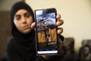 In this Monday, Oct. 7, 2019 photo, a relative shows a photo of Ahmed Manaa with his children at the family home in Majd al-Krum, Israel. Two brothers, Ahmed and Khalil Manaa, and a third man, Mohammed Sabea were recently killed in a midday shootout in Majd al-Krum, that left another Manaa brother wounded and remains in the hospital. A wave of violent crime in Israel’s Arab communities has exposed the longstanding mistrust between the marginalized community and Israeli authorities, with each side accusing the other of neglecting the problem. (AP Photo/Mahmoud Illean)