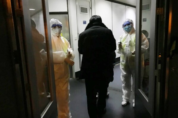Health Officials in hazmat suits wait at the gate to check body temperatures of passengers arriving from the city of Wuhan Wednesday, Jan. 22, 2020, at the airport in Beijing, China. Nearly two decades after the disastrously-handled SARS epidemic, China’s more-open response to a new virus signals its growing confidence and a greater awareness of the pitfalls of censorship, even while the government is as authoritarian as ever. (AP Photo Emily Wang)