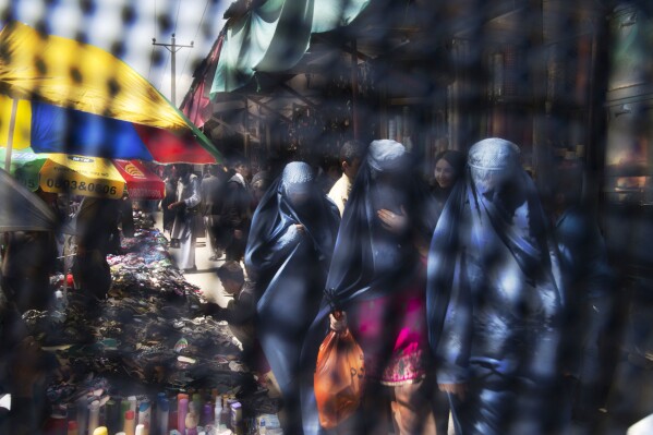FILE - Seen through the eye grid of a burqa, women walk through a market in Kabul, Afghanistan, April 11, 2013. (AP Photo/Anja Niedringhaus, File)
