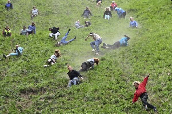 Participants compete in the women's downhill race category of the traditional annual Cheese Rolling contest at Cooper's Hill in Brockworth, Gloucestershire, England, Monday, May 26, 2025.(AP Photo/Anthony Upton)