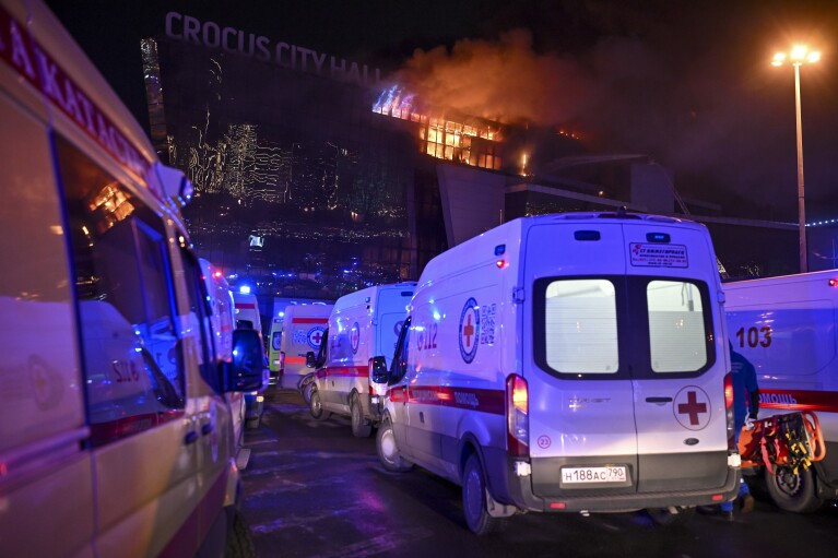 Ambulances park near a burning building of the Crocus City Hall on the western edge of Moscow, Russia, Friday, March 22, 2024. Several gunmen have burst into a big concert hall in Moscow and fired automatic weapons at the crowd, injuring an unspecified number of people and setting a massive blaze in an apparent terror attack days after President Vladimir Putin cemented his grip on the country in a highly orchestrated electoral landslide. (AP Photo/Dmitry Serebryakov)
