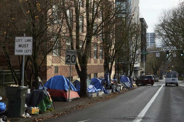 FILE - Tents line the sidewalk on SW Clay St in Portland, Ore., on Dec. 9, 2020. A group of people experiencing homelessness in Portland filed a class action lawsuit on Friday, Sept. 29, 2023, challenging the city’s new homeless camping restrictions. (AP Photo/Craig Mitchelldyer, File)