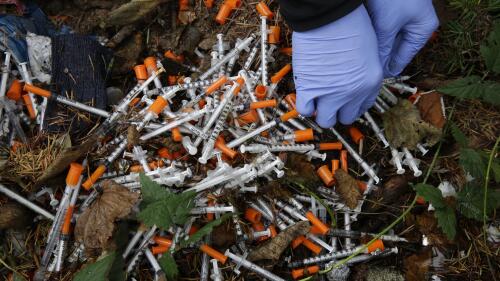 FILE - A volunteer cleans up needles used for drug injection that were found at a homeless encampment in Everett, Wash., Nov. 8, 2017. A temporary law that makes possession of small amounts of drugs a misdemeanor expires on July 1, so if lawmakers fail to pass a bill, Washington would become the second state — after neighboring Oregon — to decriminalize drug possession. Lawmakers said Tuesday, May 2, 2023, they were increasingly optimistic a compromise will be reached to avoid those consequences. (AP Photo/Ted S. Warren, File)