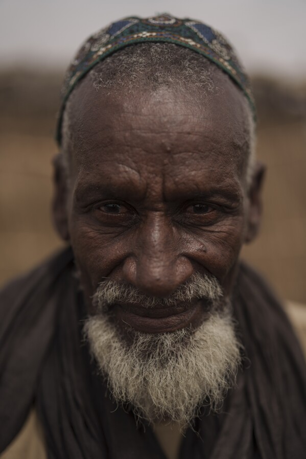 Pate Ba stands for a portrait at a local market near a water station known as Bem Bem, in the Matam region of Senegal, Wednesday, April. 19, 2023. The 70-year old herder says that the one of the main difficulties is the lack of rain but when the rainy season is good, there is water and pasture that the cattle can benefit from. "We live off our cattle but if the cattle find any difficulties, we suffer too", he says. (AP Photo/Leo Correa)