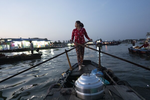 Nguyen Thi Thuy, a vendor who sells steamed buns on a floating market, paddles her boat in Can Tho, Vietnam, Wednesday, Jan. 17, 2024. On good days she makes about $4 — hardly enough to put food on the table. (AP Photo/Jae C. Hong)
