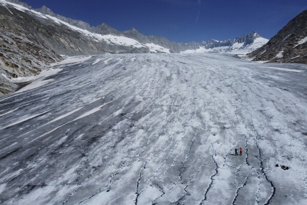 Matthias Huss, of the Federal Institute of Technology in Zurich and glacier monitoring group GLAMOS, and Monica Ursina Jaeger take measurements at the Rhone Glacier near Goms, Switzerland, June 10, 2025. (AP Photo/Matthias Schrader)