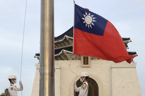 FILE - Two soldiers lower the national flag during the daily flag ceremony on Liberty Square of the Chiang Kai-shek Memorial Hall in Taipei, Taiwan, July 30, 2022. China sent navy ships and a large group of fighter jets toward Taiwan, continuing its military pressure on the island, Taiwan’s defense ministry said Thursday, Aug. 10, 2023. (AP Photo/Chiang Ying-ying, File)