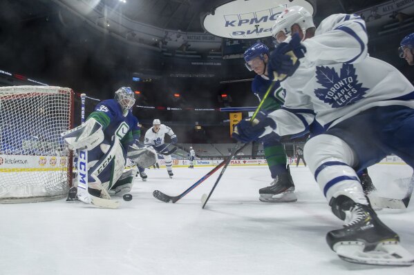 Vancouver Canucks goalie Thatcher Demko (35) makes the save as Tyler Myers, back right, checks Toronto Maple Leafs' Travis Boyd during the second period of an NHL hockey game in Vancouver, British Columbia, on Saturday, March 6, 2021. (Darryl Dyck/The Canadian Press via AP)