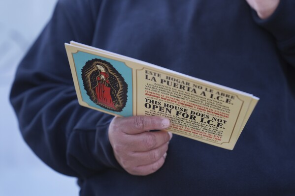A woman outside Ambiance Apparel holds a card about Immigration and Customs Enforcement after authorities conducted an operation, Friday, June 6, 2025, in Los Angeles. (AP Photo/Jae C. Hong, File)
