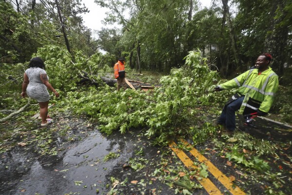 Residents of an apartment complex try to clear Old St. Augustine Road of trees and debris in Tallahassee, Fla., Friday, May 10, 2024. Powerful storms with damaging high winds threatened several states in the Southeast early Friday. (AP Photo/Phil Sears)